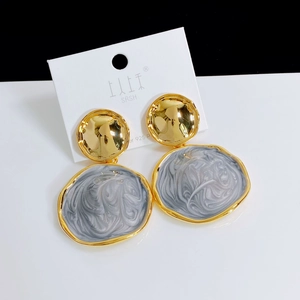 Macro detail of gold hammered metal and irregular marble resin drop earrings