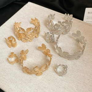Dettaglio di un set di gioielli con fiori e farfalle in oro e argento su tela ruvida