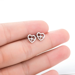 Detail of silver heart-shaped stud earrings held between fingers showing the actual size