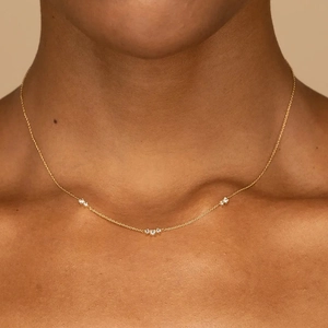 Elegant gold heart necklace with sparkling zircon clusters worn on woman's collarbone
