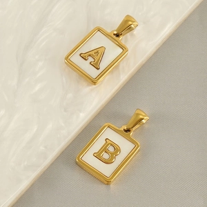 Detail view of gold rectangle pendants with white inlay featuring letters A and B
