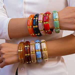 Close-up of colorful acrylic geometric bangles with gold metal beads on wrist