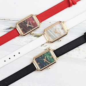 Detailed view of women's quartz watches with square gold frames and slim leather straps