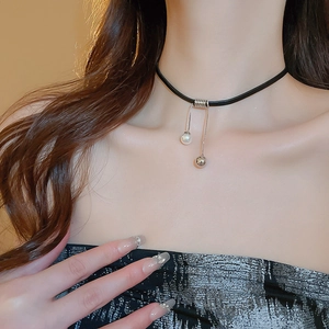 Detail of a chic black choker with a white pearl and silver metal ball pendant