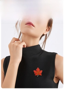 Detailed close-up of a luxury maple leaf brooch with orange rhinestones on black fabric
