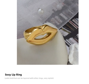 Macro shot of polished gold-plated lip-shaped ring on white ceramic and pearl accents