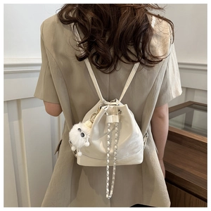 Detail of off-white PU leather bucket backpack with silver chain and cute plush pendant