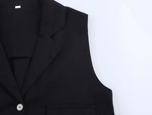 Détail du gilet noir en lin avec revers cranté et un bouton unique de couleur crème