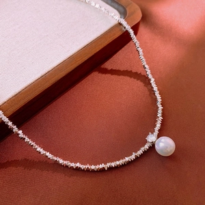Vue macro du collier de perles argentées avec pendentif en perle blanche et zircon