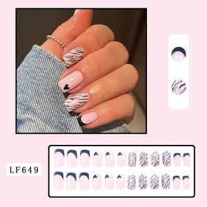 Detail of square-round press-on nails with pink base and black heart, zebra, and french motifs