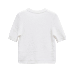Close-up of white crewneck knit sweater showing soft mohair texture and ribbed cuffs