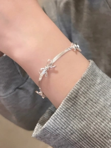 Close-up of a silver bow blade chain bracelet worn on wrist with elegant snake chain details