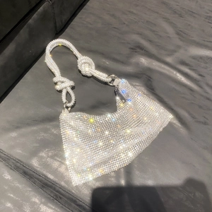 Macro shot of silver rhinestone evening bag featuring knotted strap and metal rings