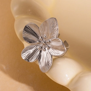 Macro shot of silver cherry blossom ring with brushed petals on a ceramic tray