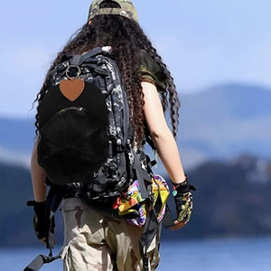 Brown heart-shaped leather hat clip holding a black cap on a camouflage backpack