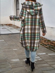 Back view of a long plaid hooded jacket in green and brown walking on autumn leaves
