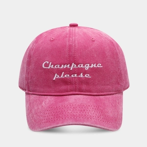 Close-up of pink washed cotton baseball cap with white Champagne Please embroidery