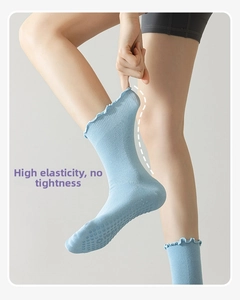 Close-up of light blue yoga socks with ruffle cuffs and anti-slip silicone dots on sole