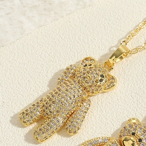 Macro shot of gold teddy bear pendant featuring micro-pave white zircons and black eyes
