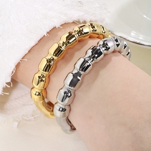Detail showing wavy textured C-shape gold and silver bracelets on wrist