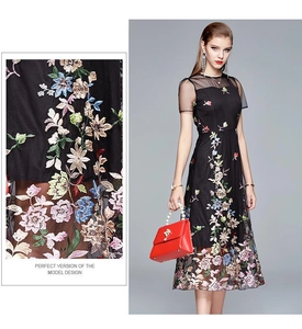 Detail of colorful floral embroidery and sheer mesh neckline on a black midi dress
