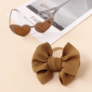 Detail of dark brown velvet bow headband and beige heart sunglasses for children