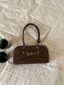 Detailed view of deep brown vintage bowling bag with metal buckles on beige fabric