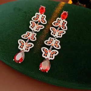 Vintage zircon butterfly tassel earrings with red gemstones on green velvet background