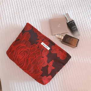 Detail of red floral embroidery vanity bag with simple wish label on quilted fabric