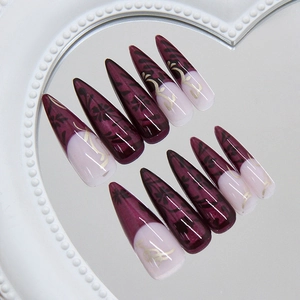 Press-on nails in deep purple stiletto shape with black floral art and gold wire detailing