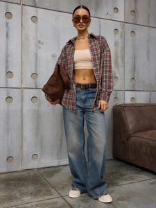 Full view of casual plaid shirt paired with blue jeans and a brown suede handbag