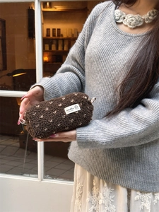Close-up of soft brown plush pencil case with embroidered puppy label and carry handle