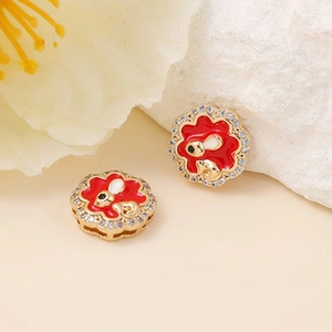 Détail macro de boucles d'oreilles fleur avec émail rouge et cristaux brillants