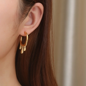 Close-up of golden irregular lava-style earrings showing liquid metal texture and polish