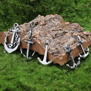 Detailed view of five vintage silver anchor pendants on natural bark and green moss background