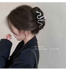 Detail of silver snake-shaped hair claw clip worn on hair with minimalist metallic finish