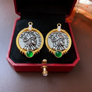 Detail of vintage coin earrings with portrait relief and green gemstone in a red box