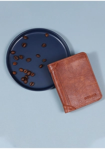 Dettaglio del portafoglio in pelle marrone con logo GIEBHIA e chicchi di caffè decorativi