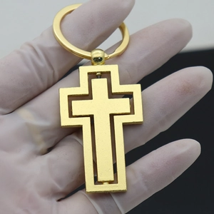 Detail of a rotating gold metal cross keychain with a unique double-layer nested design