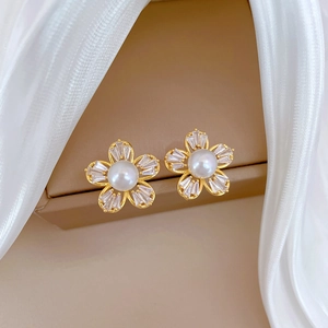 Golden flower earrings with pearls and crystals displayed on a soft jewelry box