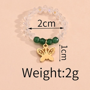 Detailed view of elastic beaded ring with green accents and gold butterfly charm charm