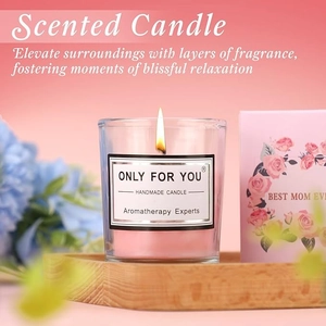 Close-up of pink glass scented candle with Best Mom Ever box and floral accents