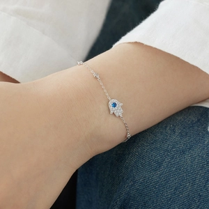 Detail of S925 sterling silver Hamsa hand bracelet with blue gemstone on wrist
