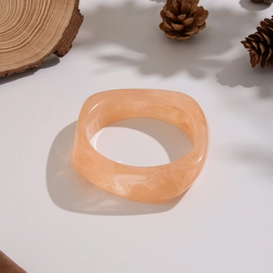 Dettaglio del bracciale largo in resina rosa marmorizzata con forma quadrata morbida