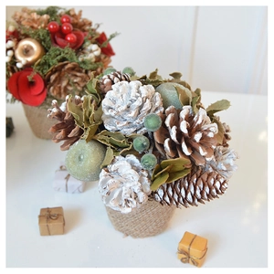 Close-up of a Christmas tabletop pine cone plant with gold berries and burlap base decor