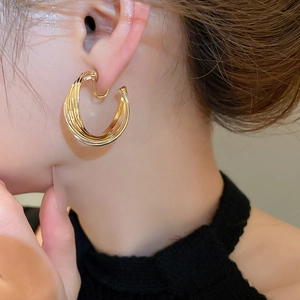 Close-up of a model wearing a golden layered twist hoop earring in a minimalist style