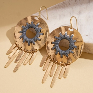 Détail de boucles d'oreilles bohèmes rondes avec cordon gris et glands métalliques