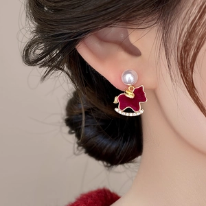 Close-up of model wearing a red flocked rocking horse earring with pearls and rhinestones