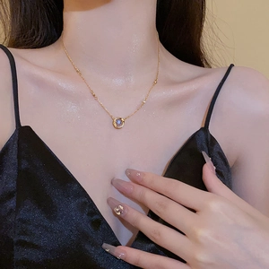 Détail du collier géométrique doré avec pendentif en zircon bleu sur robe en soie