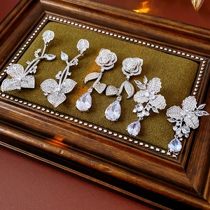 Exquisite Silberohrringe in Blumenform mit Zirkonia-Tropfen auf grünem Samthintergrund